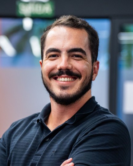 Matheus Duzzi sorrindo, de braços cruzados